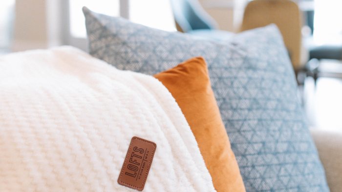 a white blanket and pillows on a couch at The Lofts at Allen Ridge