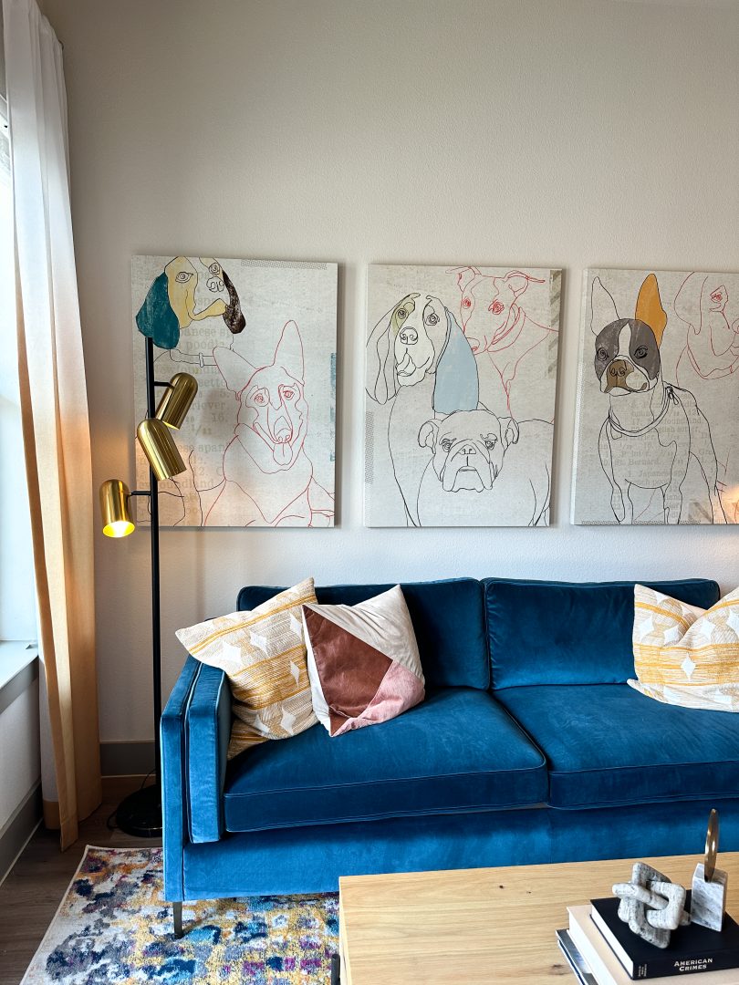 a blue couch in a living room with art on the wall at The Lofts at Allen Ridge