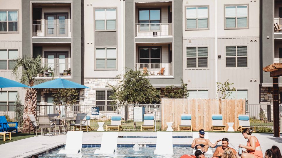 people are relaxing in the pool at an apartment complex at The Lofts at Allen Ridge