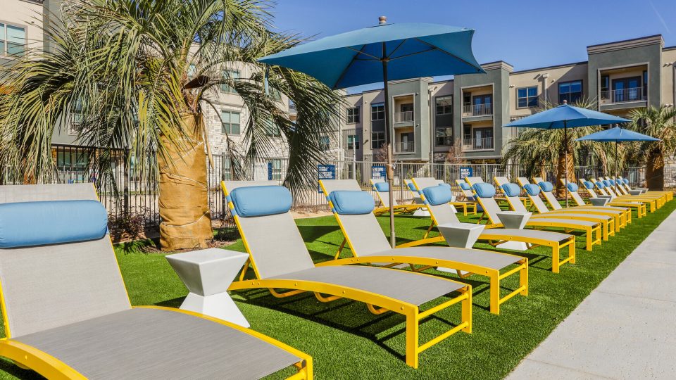 a lawn with lounge chairs and umbrellas at The Lofts at Allen Ridge