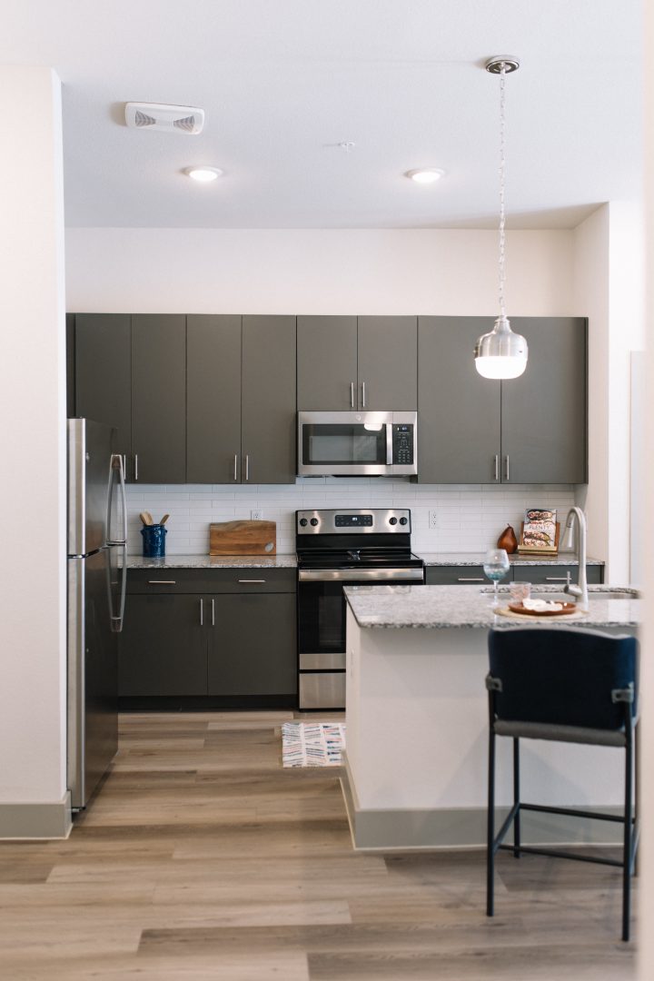 a kitchen with stainless steel appliances and gray cabinets at The Lofts at Allen Ridge